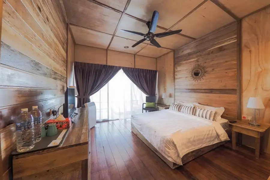 A bedroom at Dreamy Wave Dwelling Resort featuring a bed facing seamless glass doors opening onto the balcony with seaviews, authentic wooden cladding with rustic wood floors, and AC.